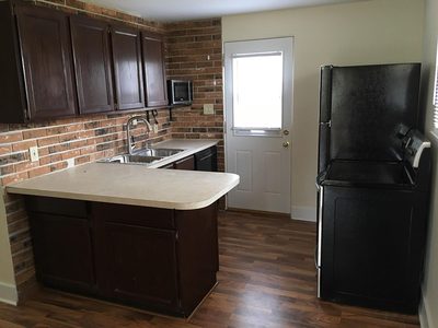 Kitchen with brick backsplash, dark cabinets and side entry door